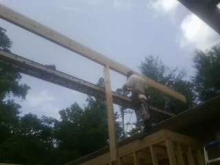 Carpenter setting a ridge beam over a new addition frame — Ice Dam Removal by Roofing Brothers in Crescent City