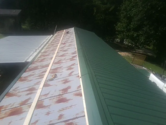 Old rusted panels beside newly installed green metal roofing — Wind Damage Roof Repair by Roofing Brothers in Crescent City