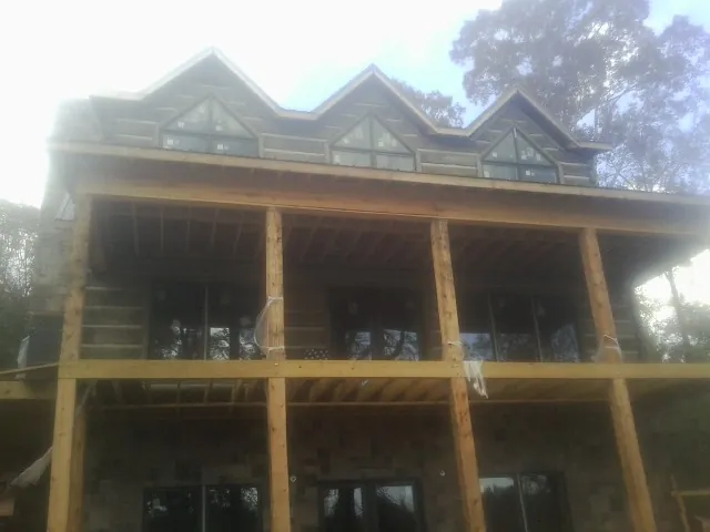 Dormers and porch framing on a large log home under construction — Roof Coating work by our crew in Crescent City