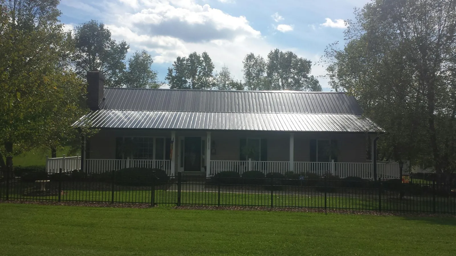 Gray metal roof on a brick ranch with a full width front porch — Gutter Guard Installation work by our crew in Crescent City