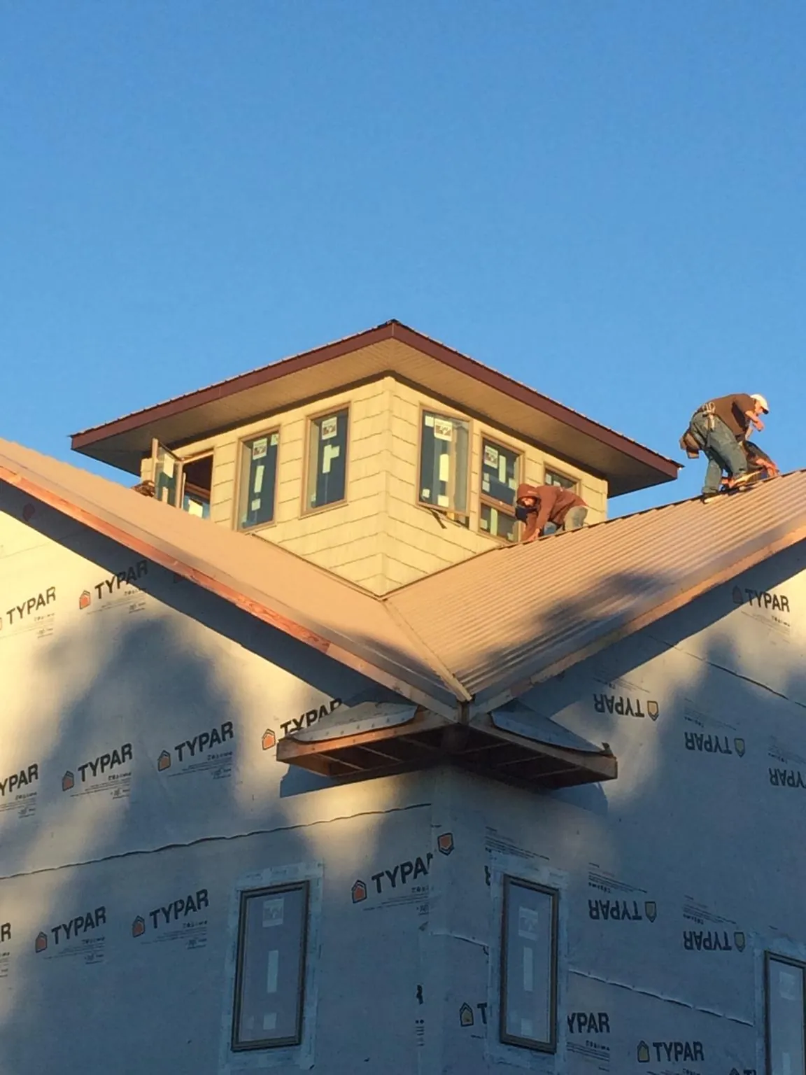 Roofers working around a rooftop cupola on a new metal roof at sunset — Roof Waterproofing in Crescent City by Roofing Brothers